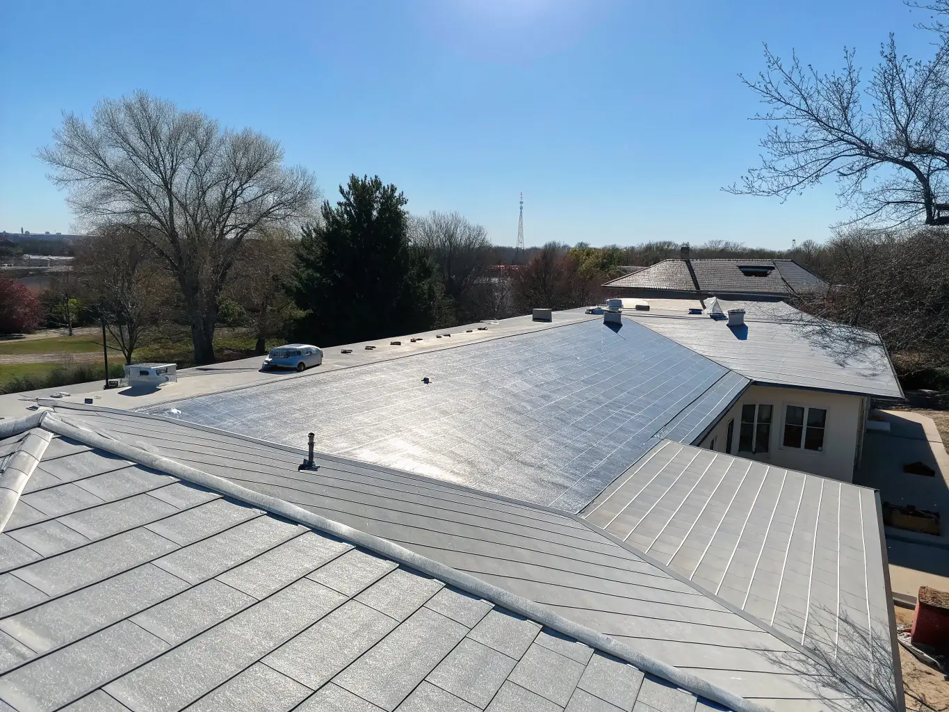An aerial view of a residential home with a TPO roof, highlighting its reflective surface and energy-saving benefits. The image captures the roof's ability to reduce heat absorption and lower cooling costs.